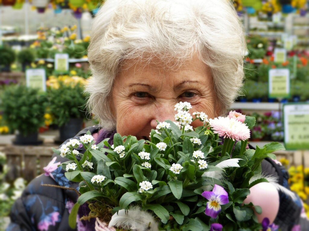 older woman smelling flowers and smiling