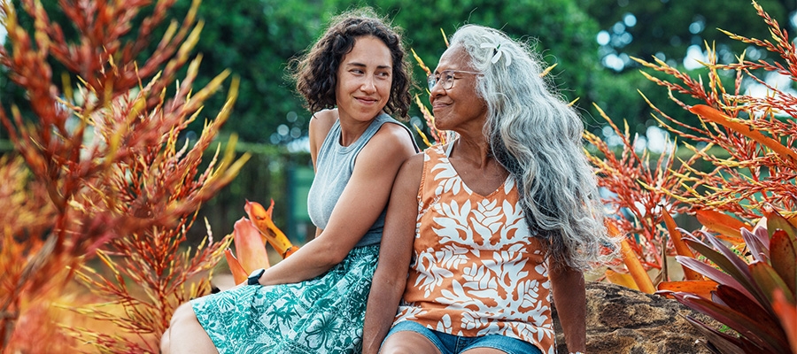 Caregiver image, older daughter and mother sitting out in nature together