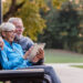 Study recruitment photo depicting and older couple on a park bench looking at an electronic tablet together