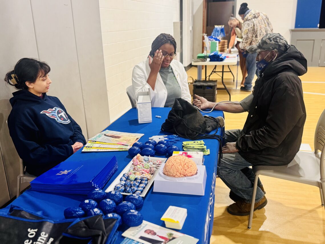 Omega Psi Phi Health Brain Aging Event photo of event participant interacting with table and having blood pressure taken