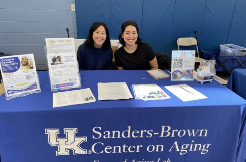 Nancy and Andrea sit behind Engaged Aging Lab table at the YMCA Senior Health Fair